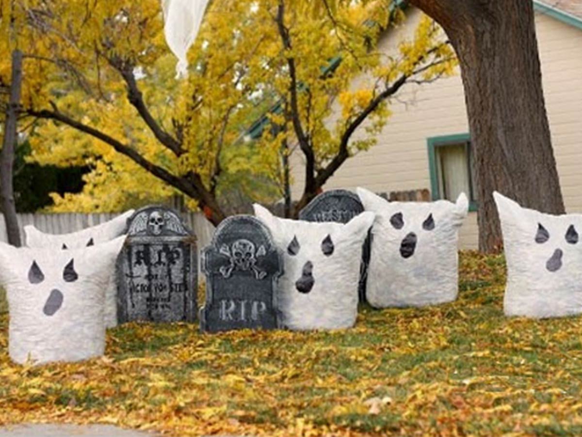 Halloweenske dekorácie v záhrade — duchovia z bielych vriec naplnených opadaným lístím