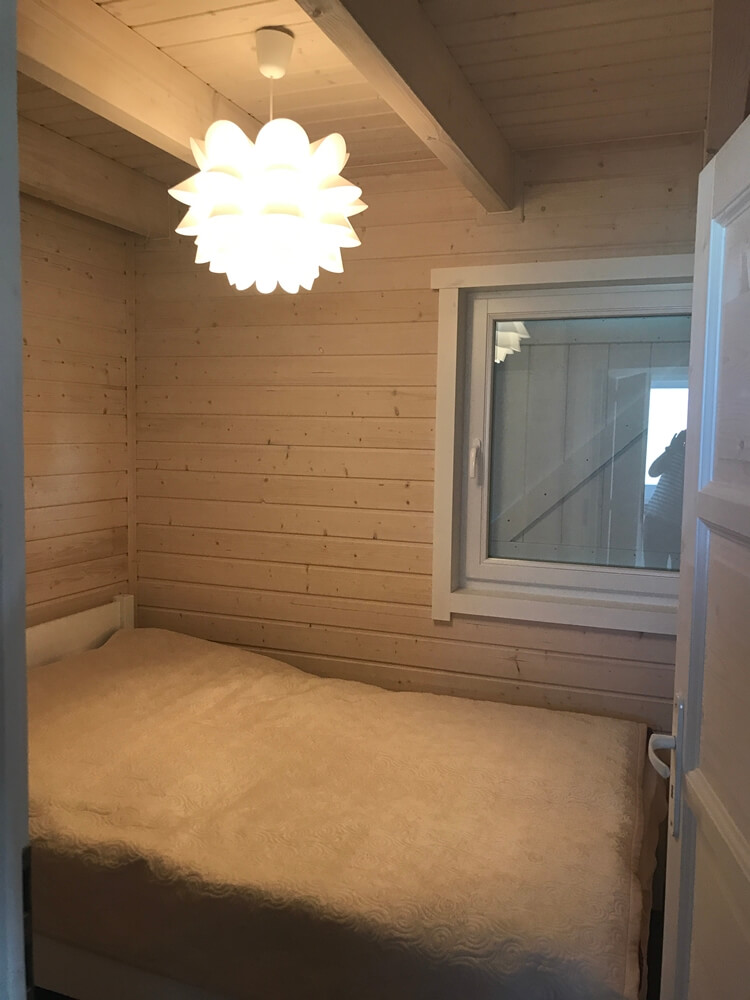 Drevená chata DALLAS – spálňa s oknom a lustrom
