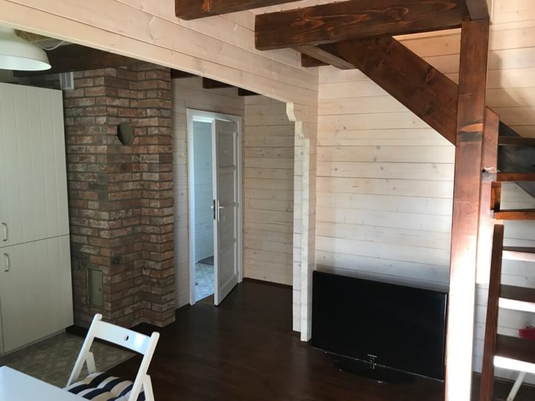 Drevená chata DALLAS – interiér s tehlovým komínom a schodiskom