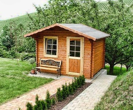 Drevený záhradný domček – domček s lavičkou pri dláždenom chodníku