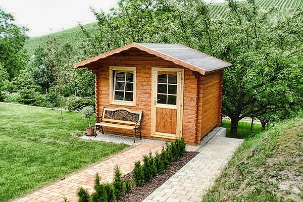 Drevený záhradný domček – domček s lavičkou pri dláždenom chodníku