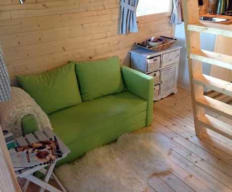 Drevený záhradný domček BUNKIE – interiér so zelenou pohovkou